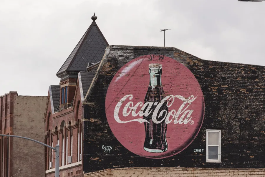 A weathered Coca-Cola ghost sign painted on dark brick in downtown Pueblo, Colorado