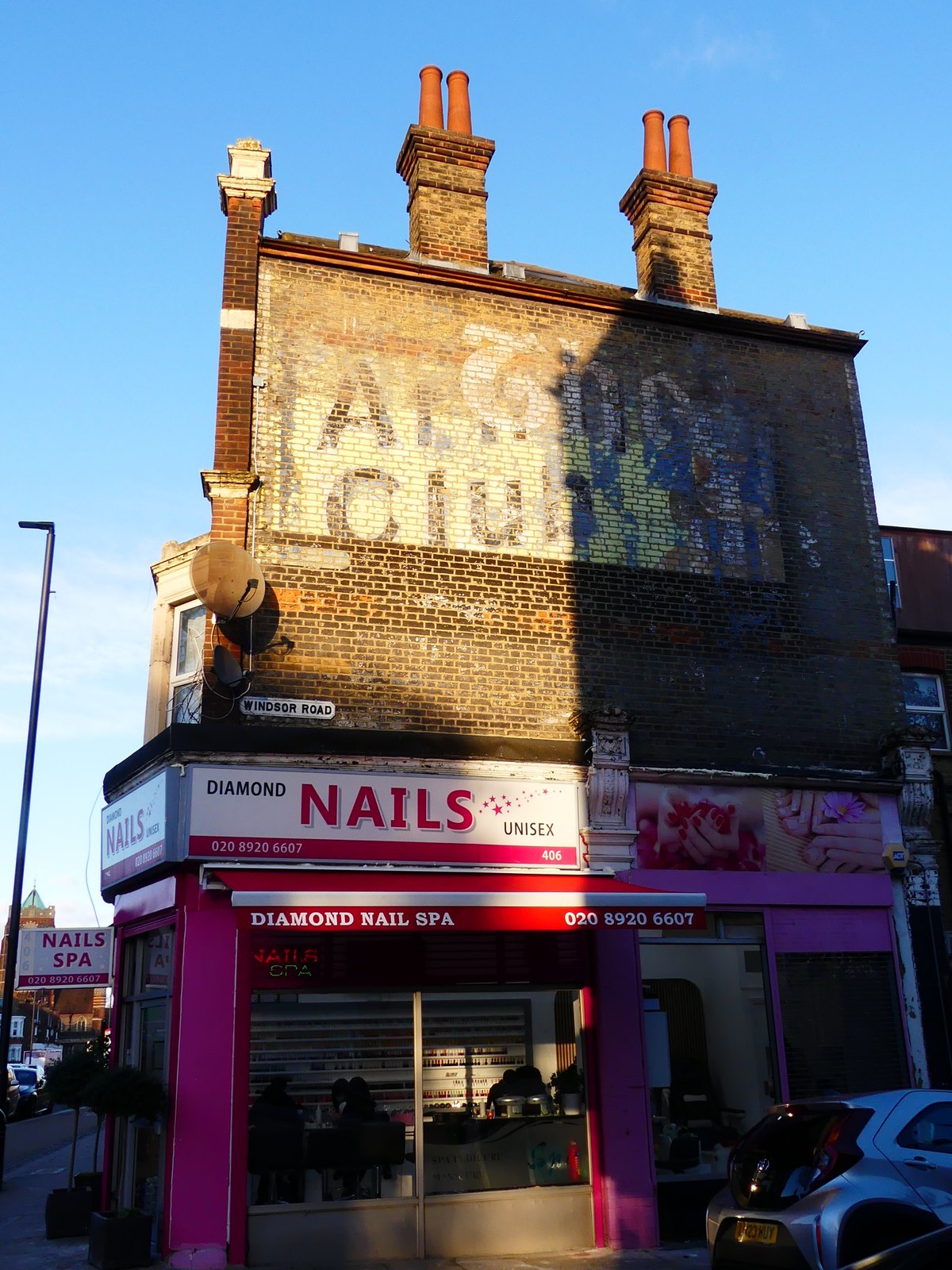 An advertising palimpsest on Windsor Road, London N13, with several generations of painted lettering overlapping on one brick wall
