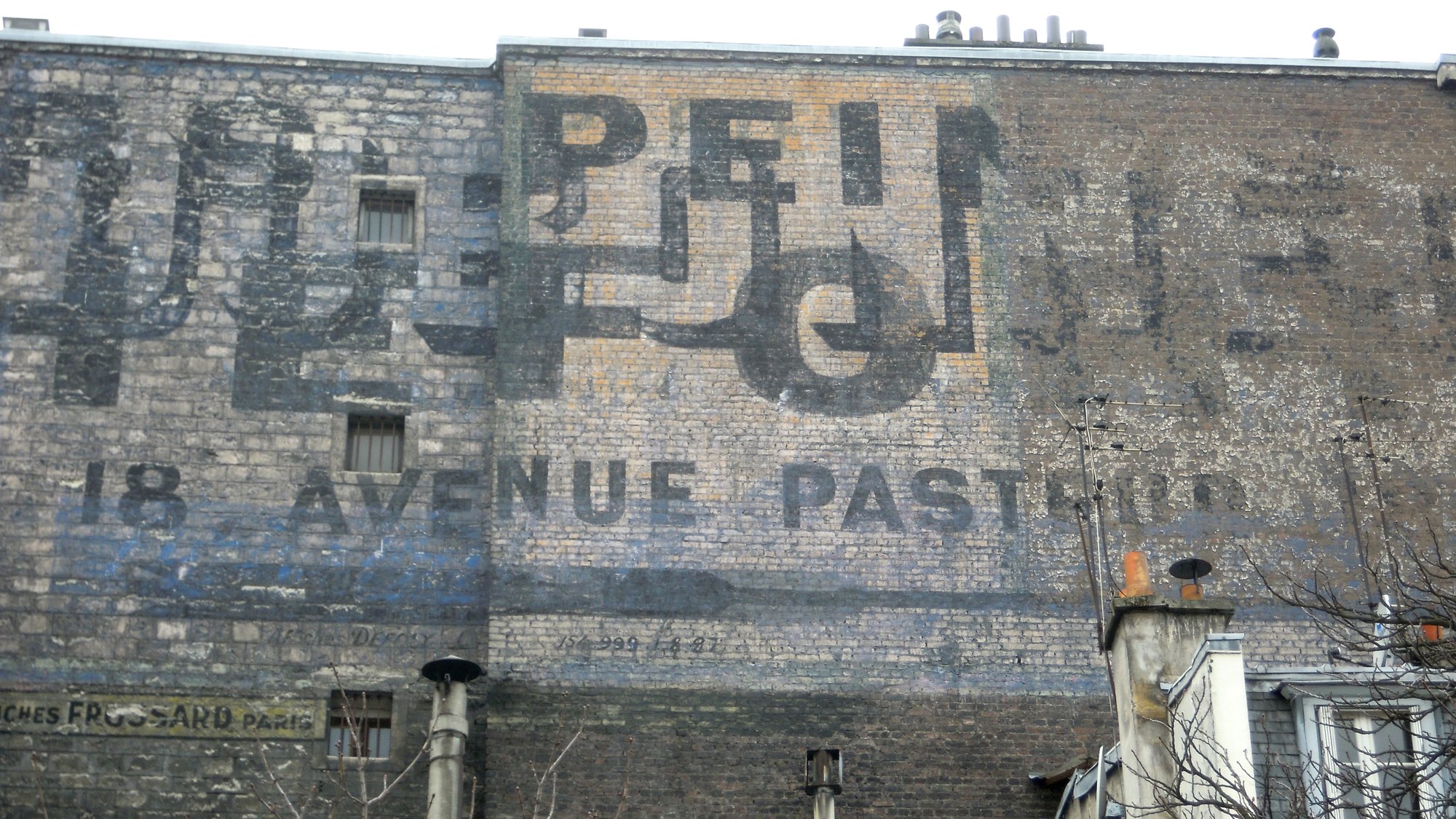 A palimpsest ghost sign on a Paris firewall: overlapping painted advertisements including the words 18 Avenue Pasteur and two billposting contractors' marks